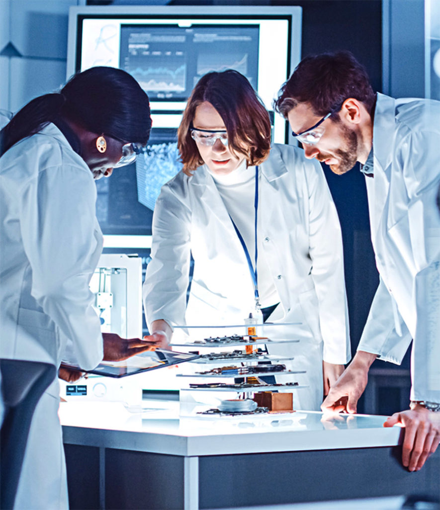 Three scientists leaning over a table looking at a tablet